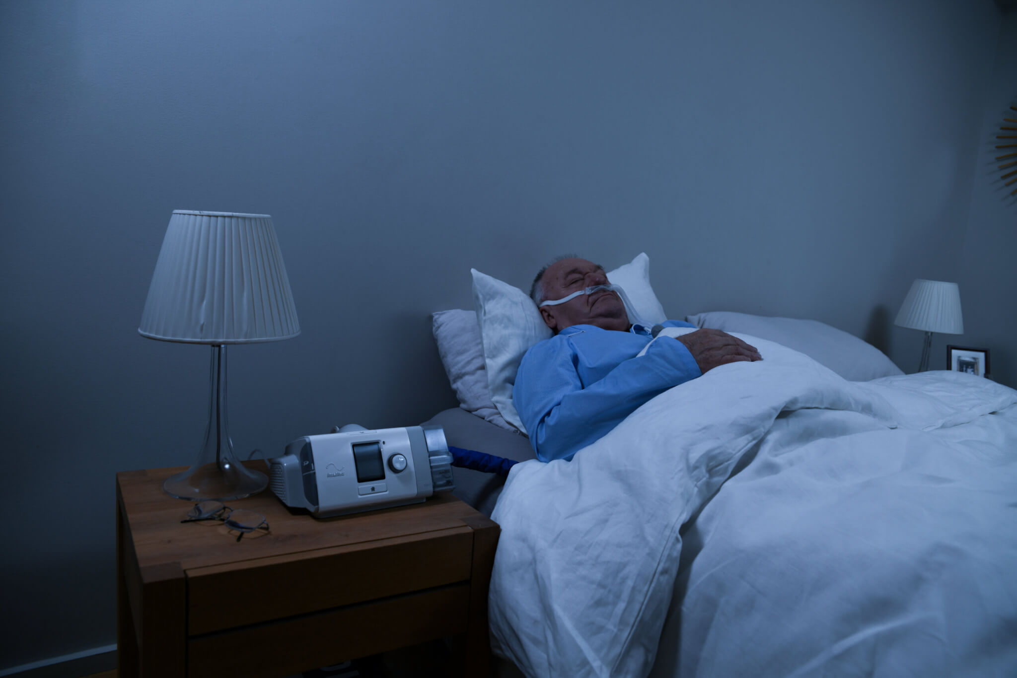 A male COPD patient sleeping in bed at home while receiving HFT