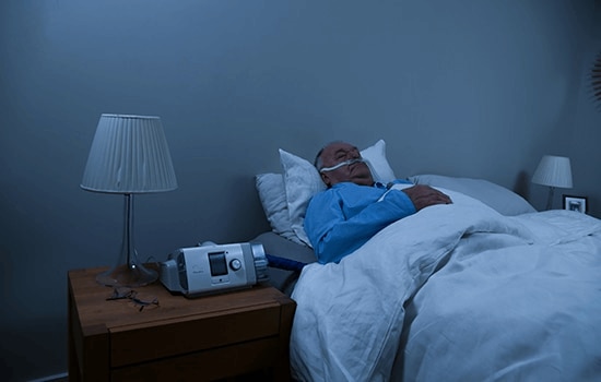 A male COPD patient sleeping in bed at home while receiving HFT