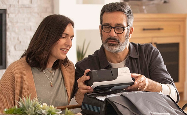 A sleep apnoea patient and his wife unboxing a ResMed Air11 device.